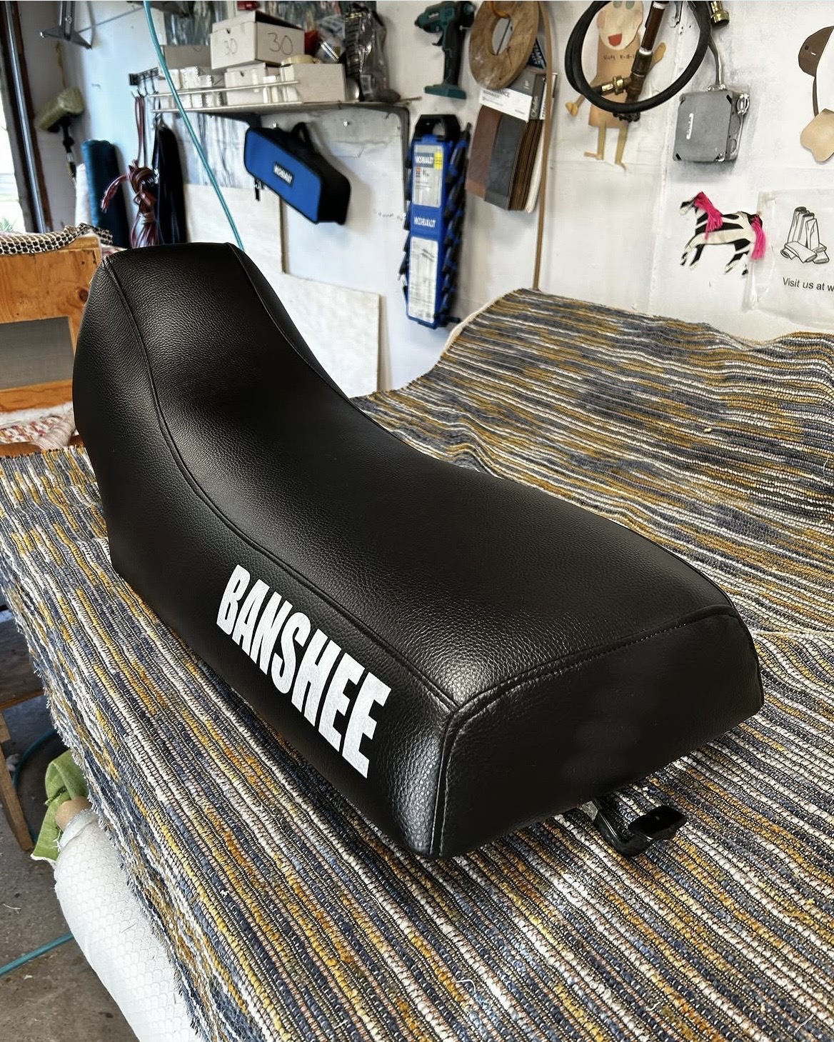 Yamaha Banshee ATV seat after restoration — new black vinyl with custom lettering, Bellport workshop