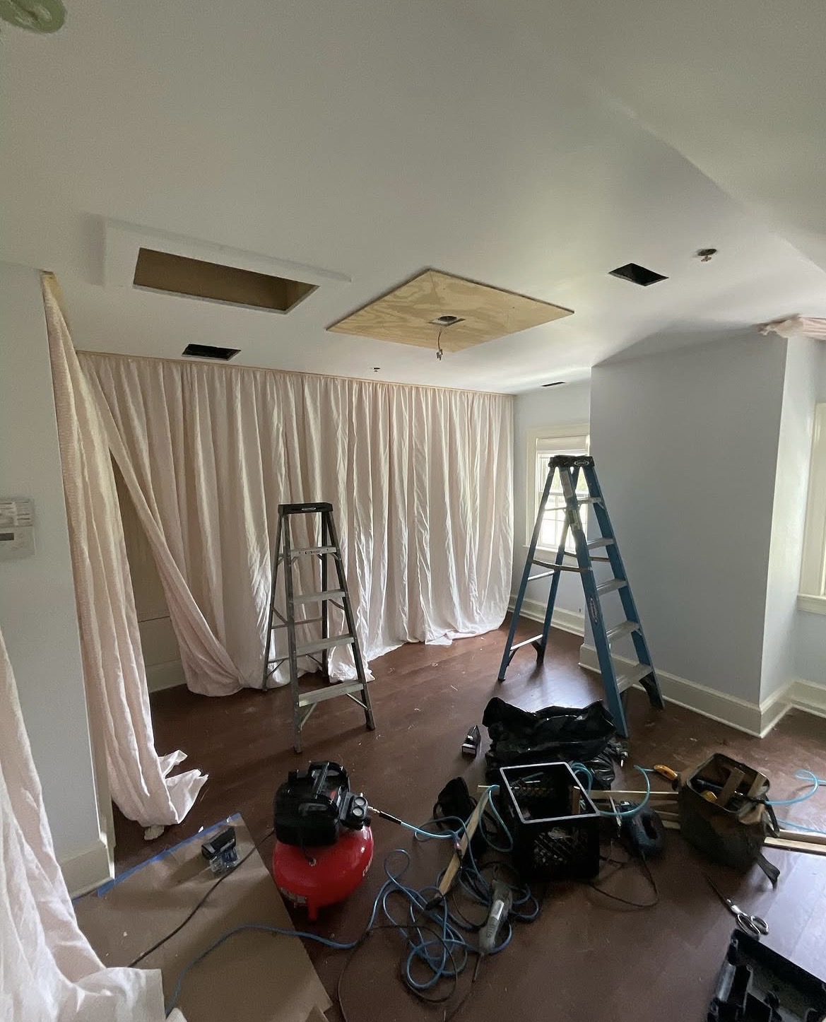 Bedroom under construction — fabric draped on walls, ladders, tools on floor
