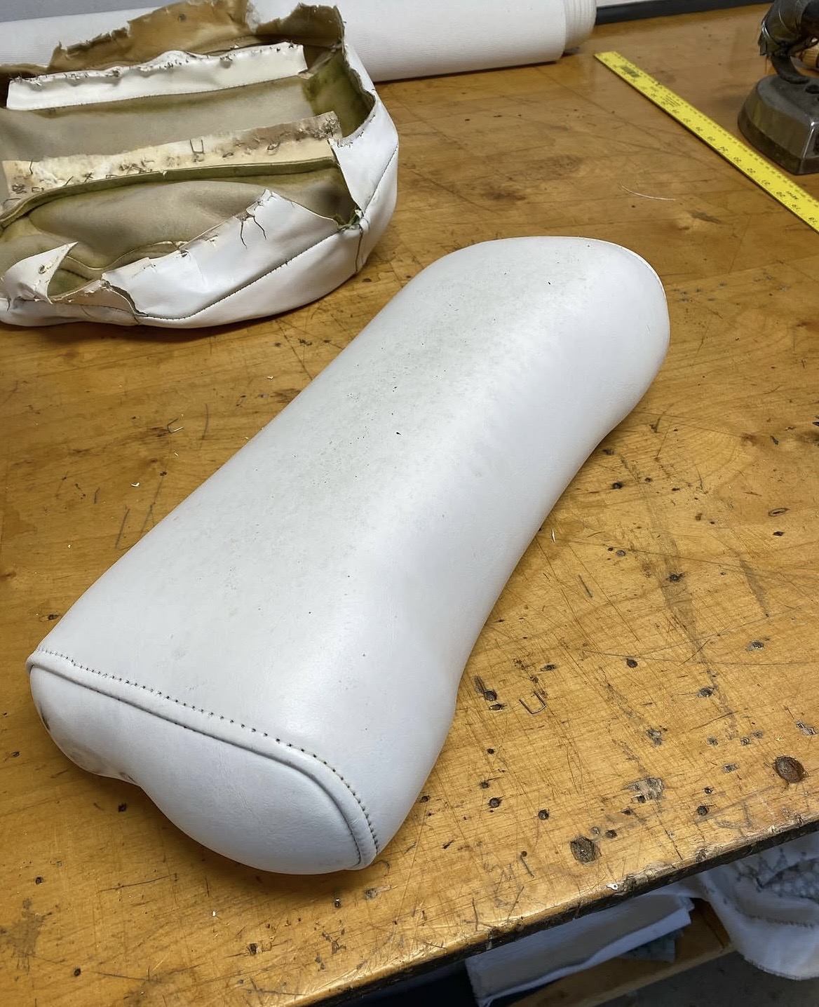 Marine upholstery before and after — worn boat cushion replaced with new white vinyl, Long Island marine reupholstery