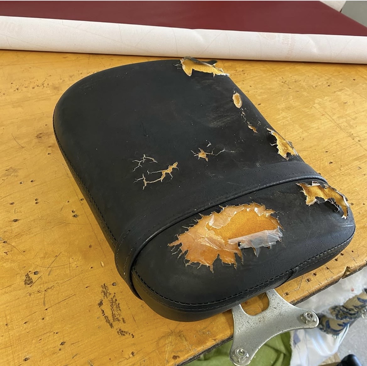 Motorcycle seat before restoration — cracked and peeling black vinyl, Bellport NY upholstery shop