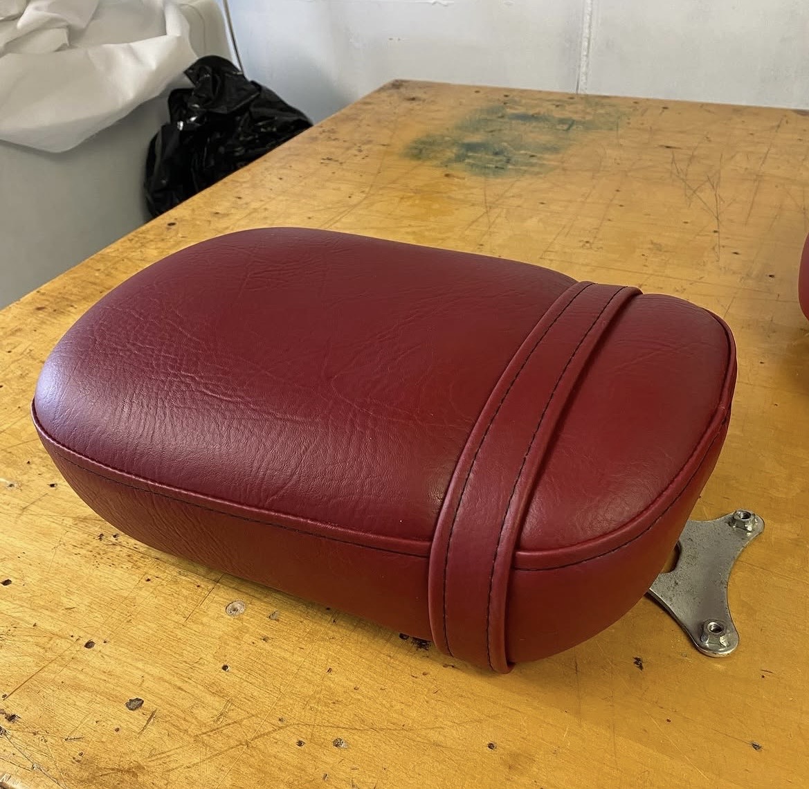 Motorcycle seat after restoration — reupholstered in burgundy vinyl with double-welt trim, Fabricio's Upholstery