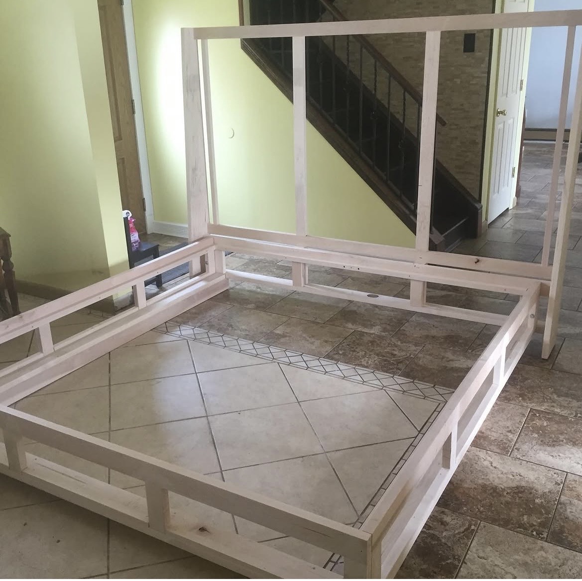 Custom bed frame — bare wood platform base and headboard skeleton before upholstery