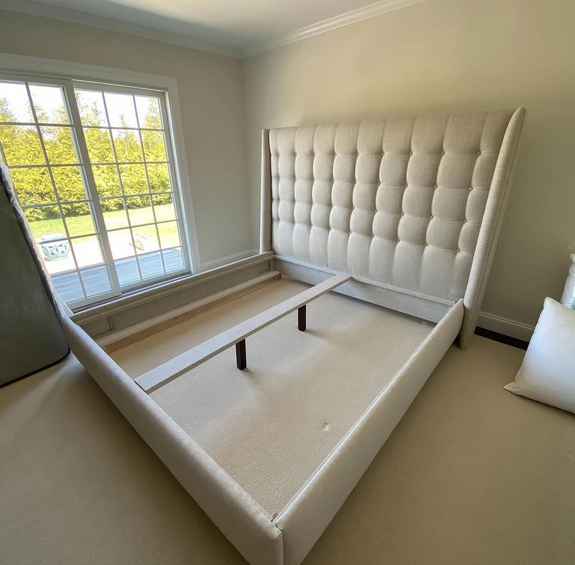 Custom upholstered bed — aerial view showing tufted headboard and platform base with slats installed